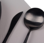 Black, white, and silver tableware set featuring ceramic plates, placemats, and napkin rings