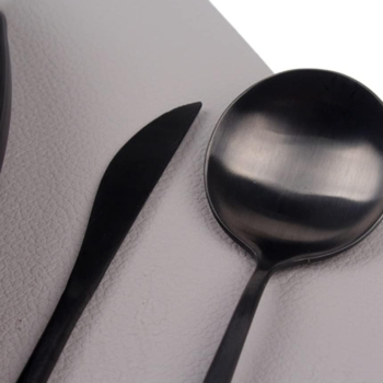Black, white, and silver tableware set featuring ceramic plates, placemats, and napkin rings